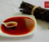 Vanilla extract in a dish with a bundle of vanilla pods